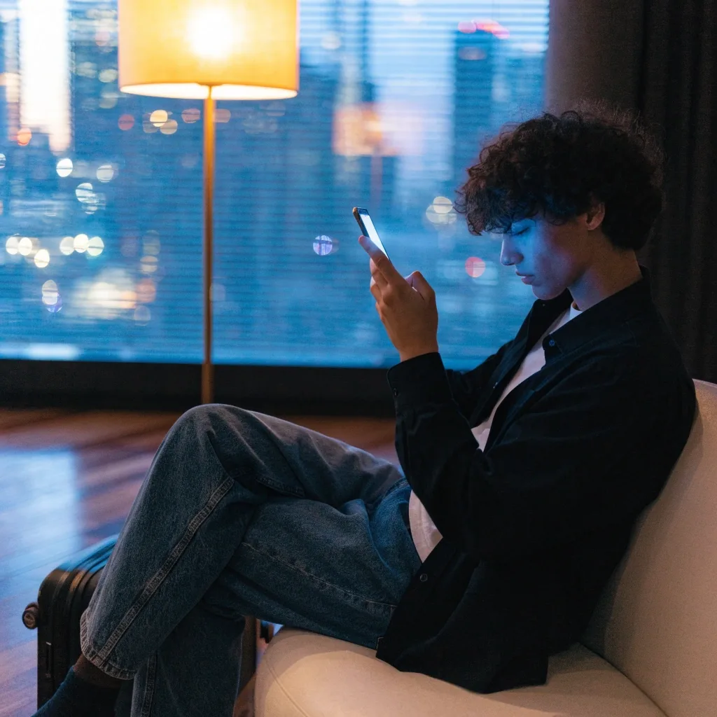 Hotel desk at dusk with a laptop and travel belongings nearby